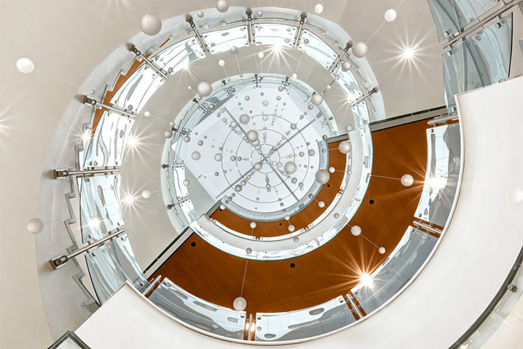 Glass railing on spiral staircase at Colorado State University Health and Medical Center - Trex Commercial Products’ Equinox glass railing provides the perfect accompaniment to the building’s circular staircase and overlooks without distracting from the distinctive architectural details and cascading art installation.